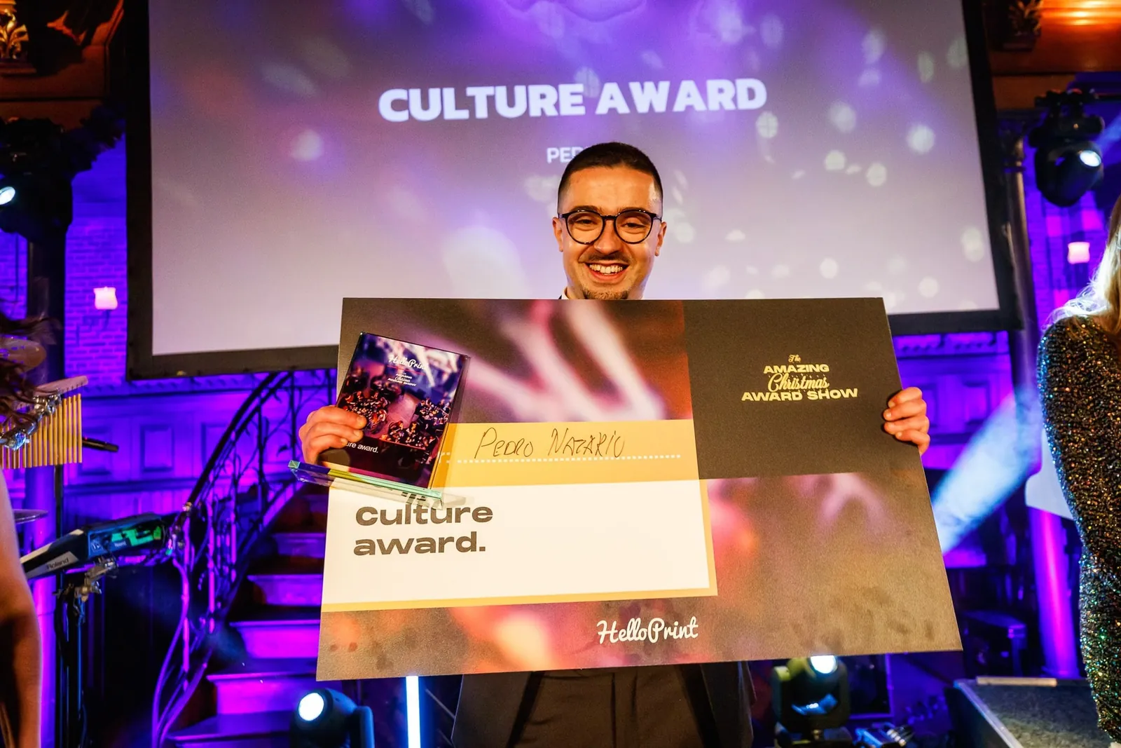 Pedro Nazário holding the HelloPrint Culture Award on stage